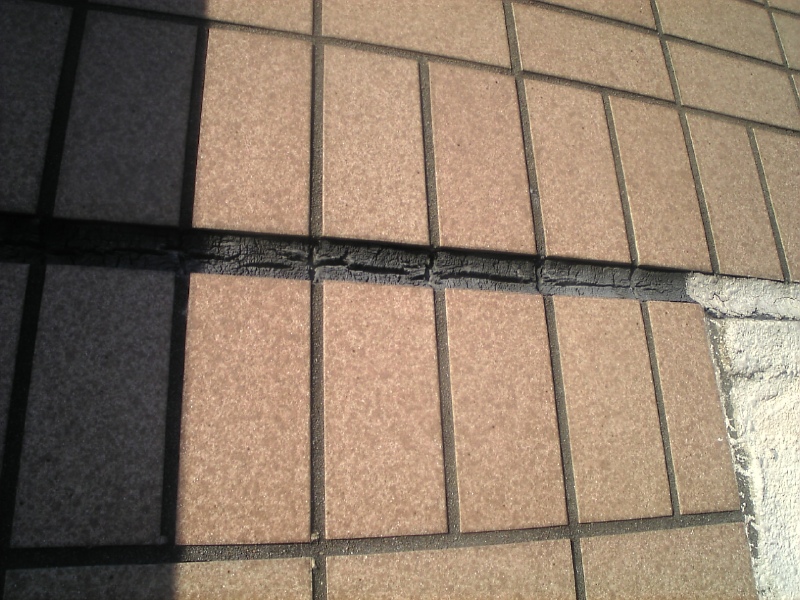 タイル面の打継目地シーリングの劣化。中央部からきれいに割れている。右の塗装保護部は同様の劣化がないので、暴露による劣化か。