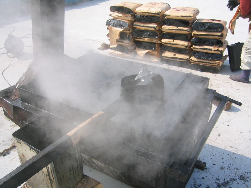 アスファルトコンパウンドの例。固形のコンパウンド（右奥）を、溶融釜（手前）内で溶かしている。