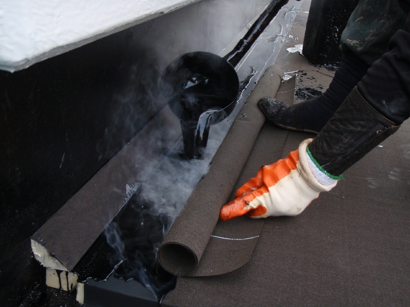 アスファルト防水熱工法の施工例。溶融コンパウンドでアスファルトルーフィングを貼り付ける。