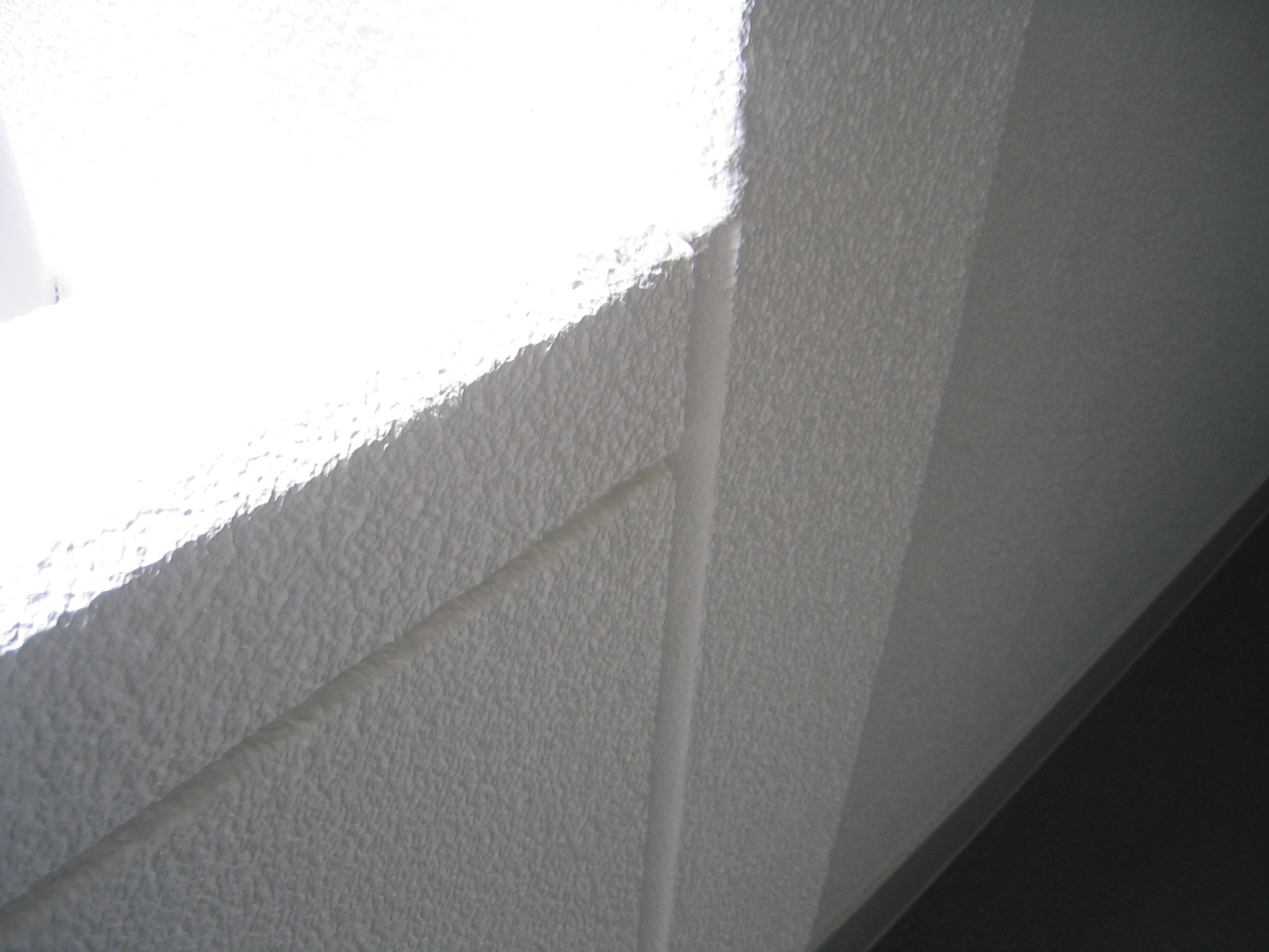 壁面と腰壁の取り合いの割れを補修。ひび割れに沿って目地を作成し、シーリング材を充填する。