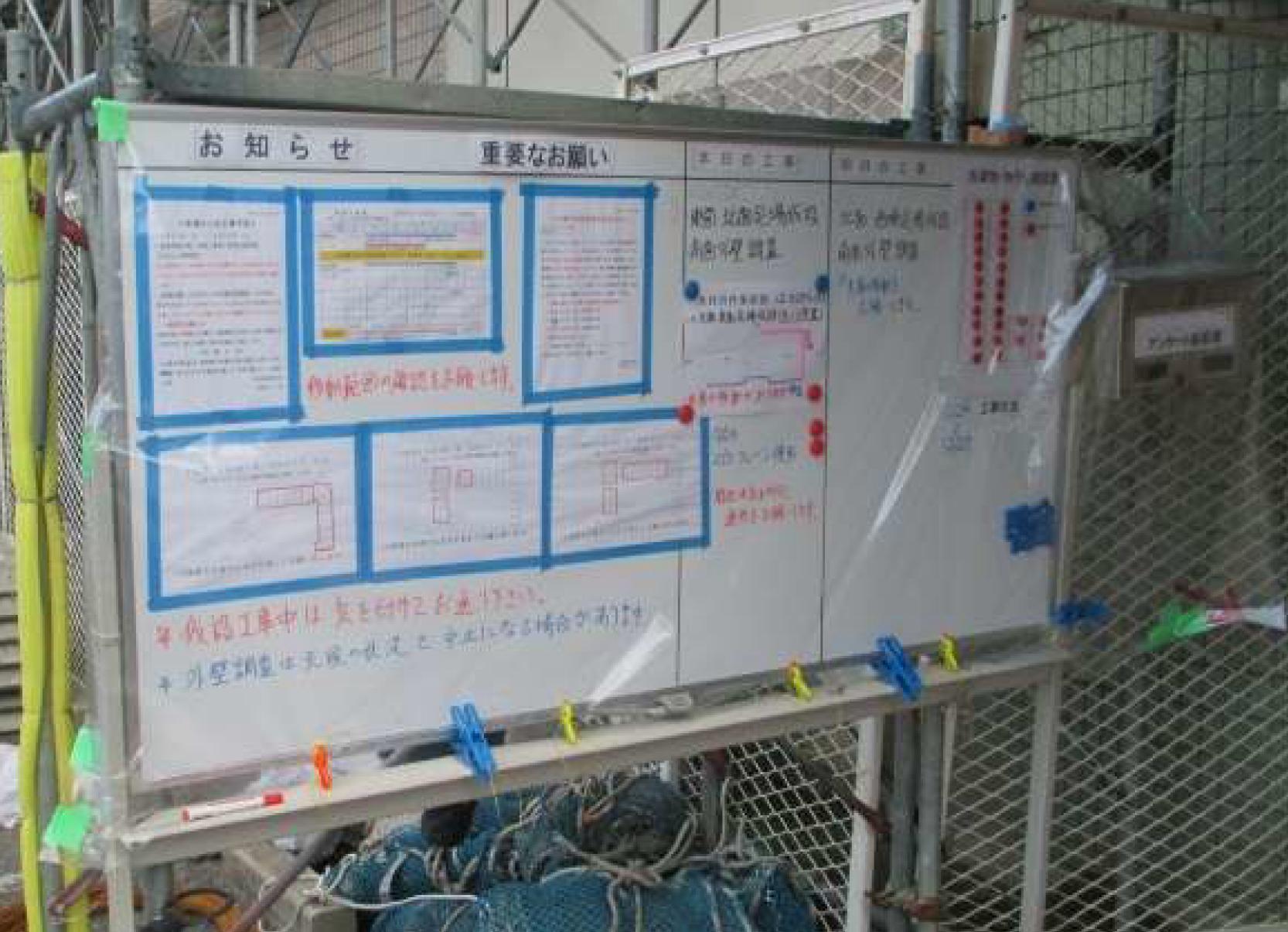 工事用掲示板の例。エントランスが狭いなどの都合で、外部に設置しなければならないこともある。その場合は雨が降っても大丈夫なように養生する。