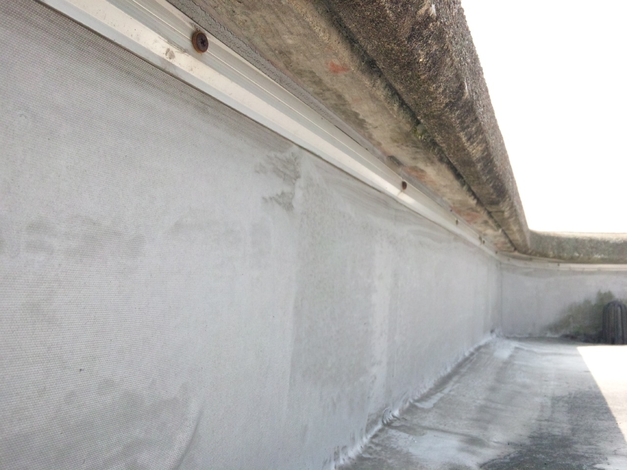 パラペットのあご下の溝は「水切り」。水切りがあるから防水端末のシーリング材に雨水が行くのを防いでいる。水切りの右側と左側で、雨水が流れているかそうでないかが、色で分かる。