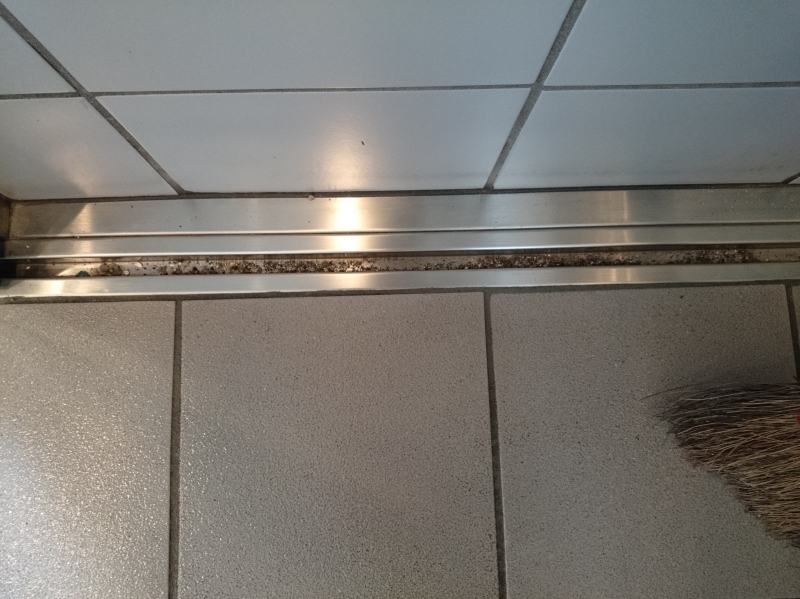 自動ドアの溝の清掃前。大規模修繕工事のゴミが溜まっている。