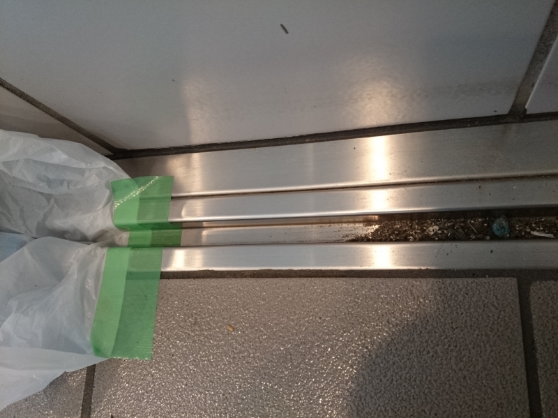 自動ドアの溝の清掃中。一部をきれいにしてそこにマスカーを貼る(ごみ袋と養生テープでも出来る）。